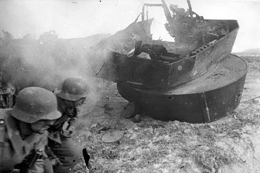 Немецкие солдаты бегут мимо разрушенного Т-26 во время боев...